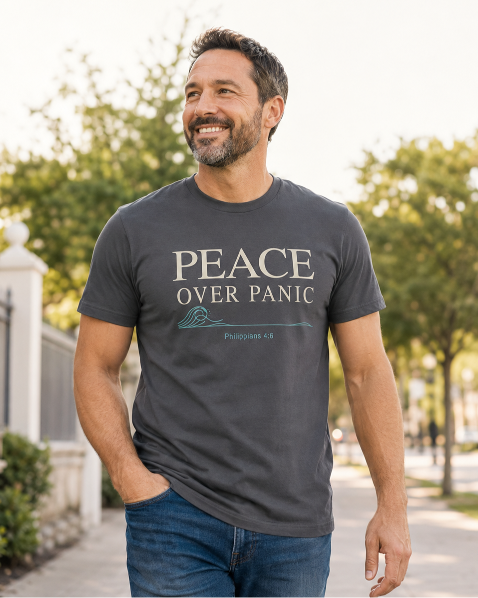 Man wearing a dark gray Peace Over Panic Christian T-shirt featuring Philippians 4:6 while walking outdoors.