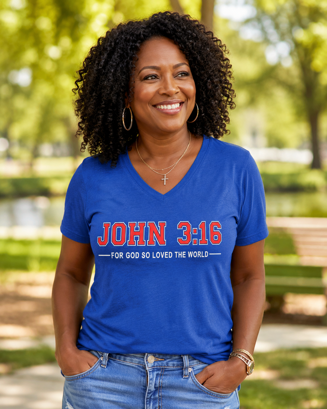 Woman wearing a royal blue John 3:16 Christian V-neck T-shirt with “For God So Loved the World” design in a sunlit outdoor setting.