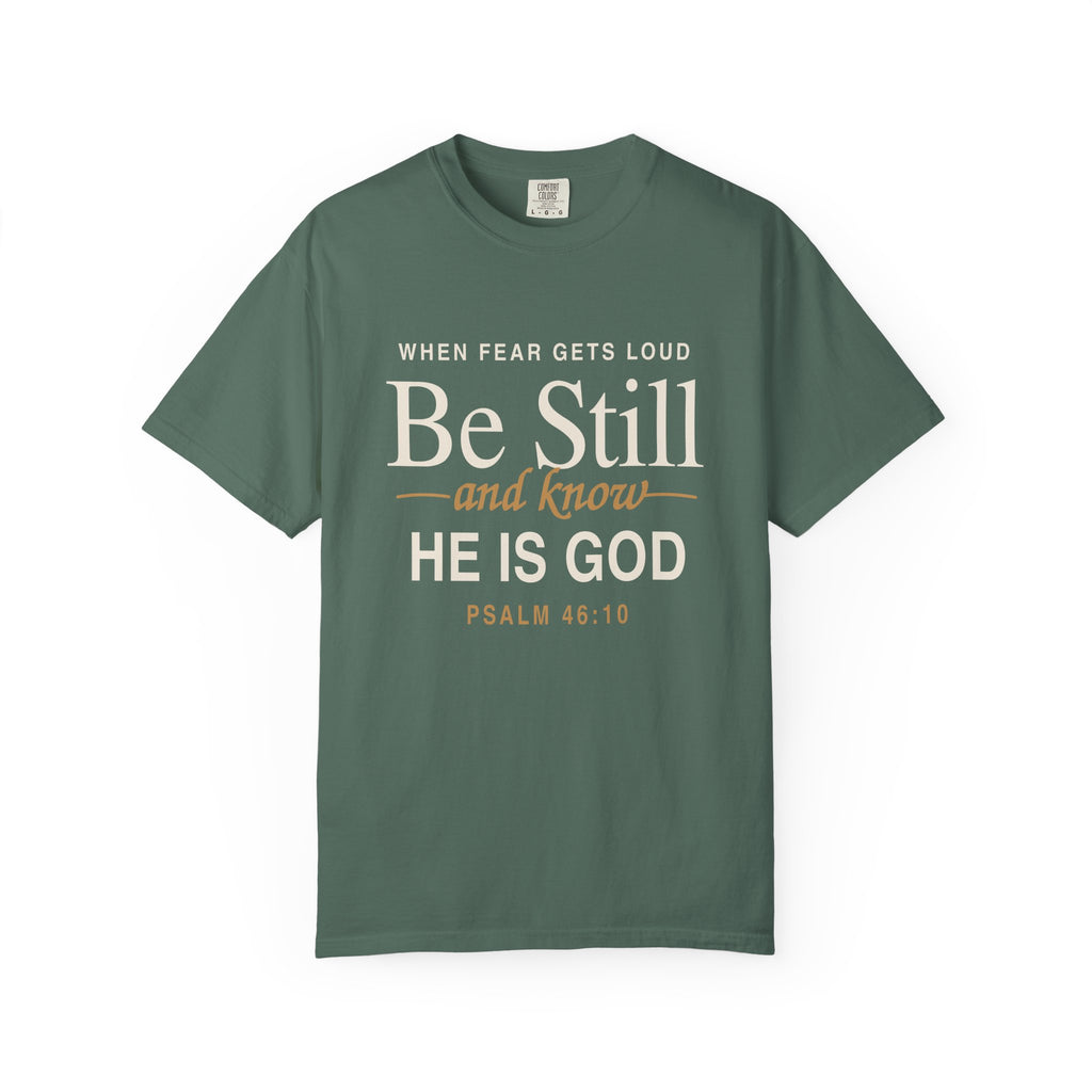 Light green Christian T-shirt reading “When Fear Gets Loud, Be Still and Know He Is God” with Psalm 46:10 on a plain white background.