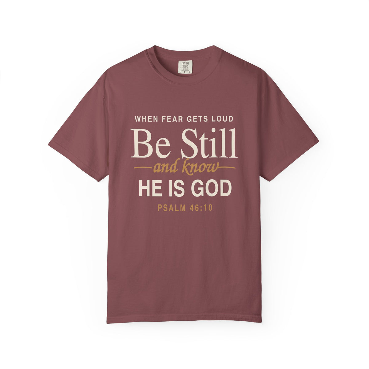 Maroon Christian T-shirt reading “When Fear Gets Loud, Be Still and Know He Is God” with Psalm 46:10 on a plain white background.