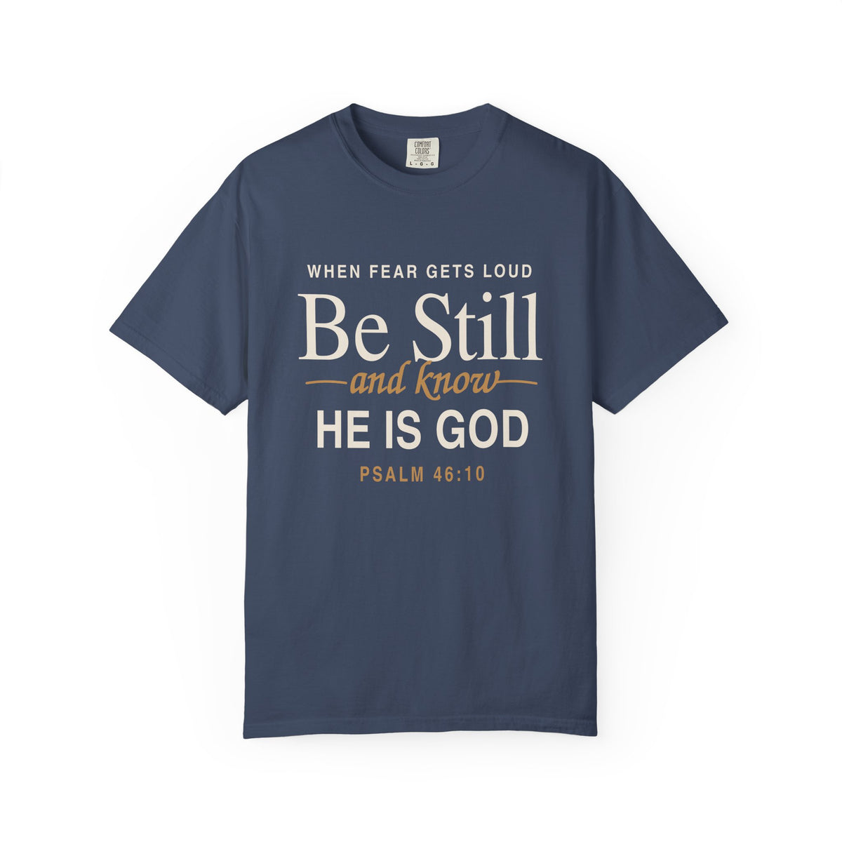 Light blue Christian T-shirt reading “When Fear Gets Loud, Be Still and Know He Is God” with Psalm 46:10 on a plain white background.