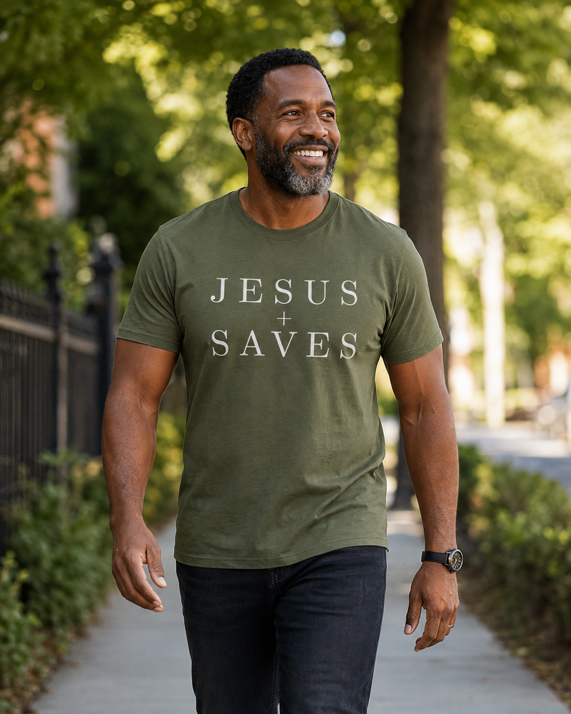 Man wearing olive Jesus Saves shirt walking along a tree-lined sidewalk