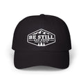 A black baseball cap with a white embroidered graphic on the front featuring a mountain and pine tree design, with the text 'BE STILL AND KNOW PSALM 46:10'.