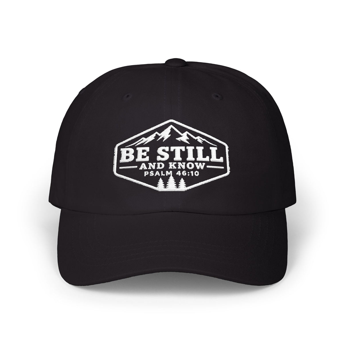 A black baseball cap with a white embroidered graphic on the front featuring a mountain and pine tree design, with the text 'BE STILL AND KNOW PSALM 46:10'.