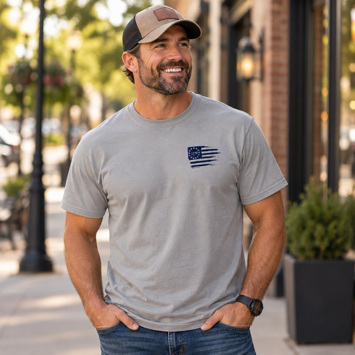 Man wearing gray Christian T-shirt with small navy distressed 1776 flag graphic on left chest.