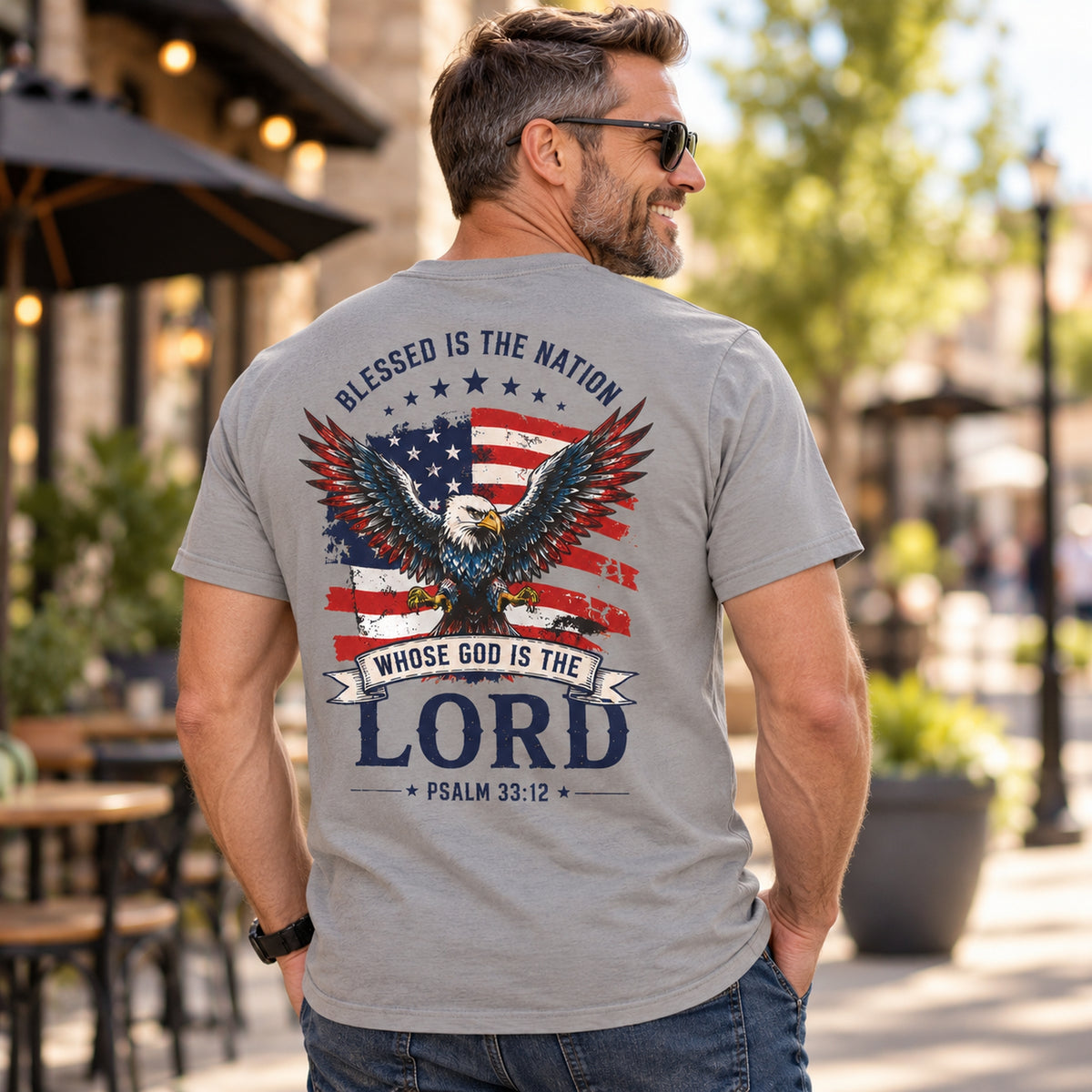 Man wearing gray Blessed Is the Nation Christian shirt showing eagle, American flag, and Psalm 33:12 back artwork.