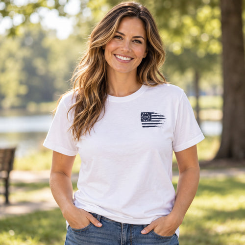 Woman wearing white Christian crew-neck T-shirt with small distressed 1776 American flag graphic on left chest.